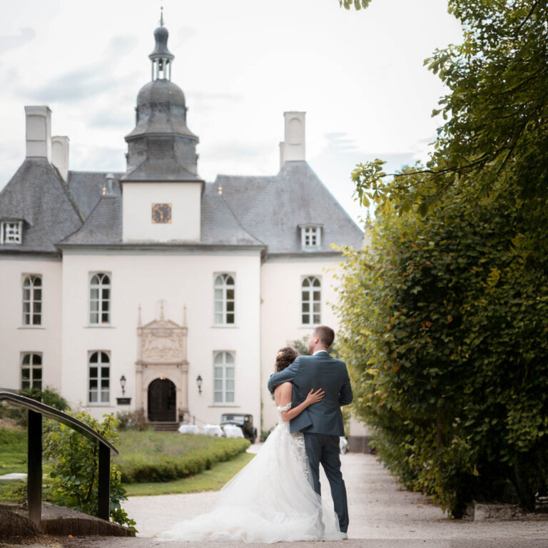 Romantische Hochzeitsfotografie: Du und dein Partner genießt innig euren besonderen Moment vor einem eleganten Schloss, während das historische Ambiente eure Liebe in stilvoller Kulisse unvergesslich macht.